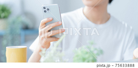 リビングでスマホを操作する若い男性の手元のアップ バナーサイズ リビングでスマホを操作する若い男性の手元のアップ バナーサイズ 75633888