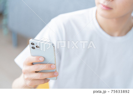 リビングでスマホを操作する若い男性の手元のアップ リビングでスマホを操作する若い男性の手元のアップ 75633892