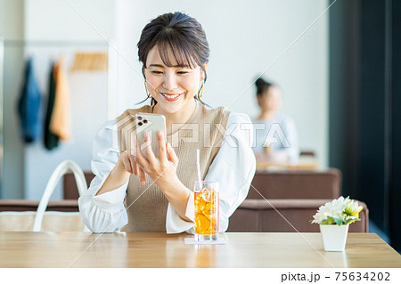 カフェでスマホを見る若い女性 カフェでスマホを見る若い女性 75634202