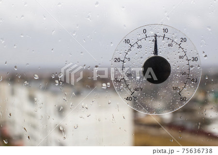 Outdoor outdoor thermometer of air temperature outside the window on which there are raindrops. Concept early spring, cold weather with rain, copy space for text 75636738