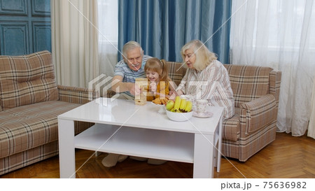 Excited child girl kid involved in build blocks board game with senior grandmother and grandfather Excited child girl kid involved in build blocks board game with senior grandmother and grandfather 75636982