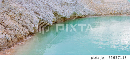 Shore with white clay close-up, turquoise azure water in pond, shallow lake with clear blue water. 75637113