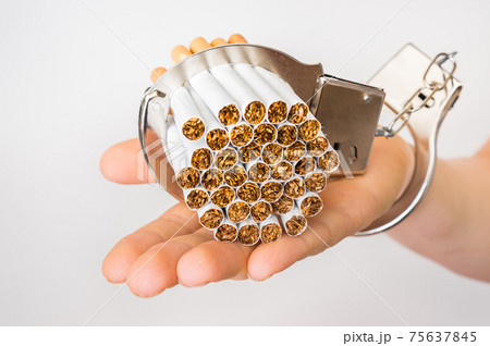 Female hand with handcuffs and cigarettes on white Female hand with handcuffs and cigarettes on white 75637845