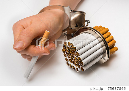 Female hand with handcuffs and cigarettes on white 75637846