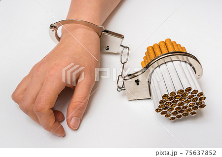 Female hand with handcuffs and cigarettes on white Female hand with handcuffs and cigarettes on white 75637852
