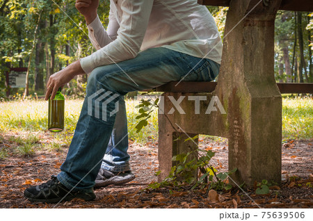 Lonely drunk man with beer bottle sitting on bench Lonely drunk man with beer bottle sitting on bench 75639506