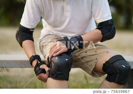 Skateboard safety gear and pads. Asian man with surfboards or surf skate around city streets background on a summer day. Free relax lifestyle and millennial trend concept Skateboard safety gear and pads. Asian man with surfboards or surf skate around city streets background on a summer day. Free relax lifestyle and millennial trend concept 75639867