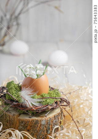 Easter decor in a natural style. Eggshell with flowers in the nest 75643383