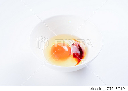 白い器に入れた綺麗な生卵にしょうゆを注ぐ 白バックの写真素材
