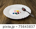 A bunch of pills on a plate 75643837