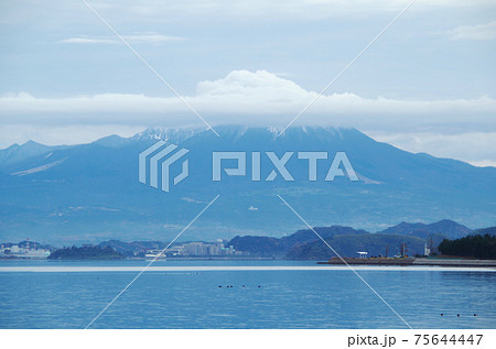 中海の岸から眺める大山の上空に大山を模写した形の雲が掛かっている風景 島根県 安来市 曇り の写真素材