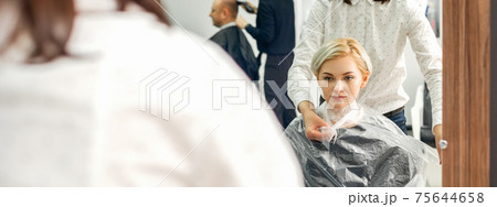 Hairdresser puts on transparent cape 75644658