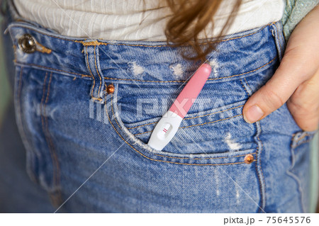 Young woman with positive pregnancy test in pocket of jeans close-up Young woman with positive pregnancy test in pocket of jeans close-up 75645576