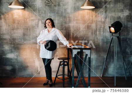 A businesswoman in a white shirt and pants stands in her office 75646380
