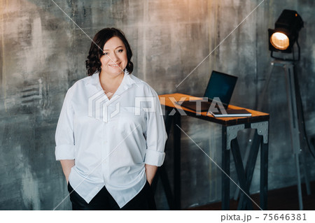 A businesswoman in a white shirt and pants stands in her office A businesswoman in a white shirt and pants stands in her office 75646381