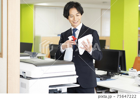 会社で共用のコピー機(複合機)の除菌掃除をする男性 会社で共用のコピー機(複合機)の除菌掃除をする男性 75647222