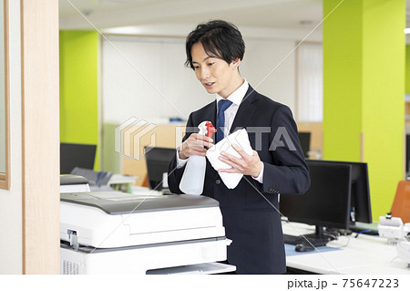 会社で共用のコピー機(複合機)の除菌掃除をする男性 会社で共用のコピー機(複合機)の除菌掃除をする男性 75647223