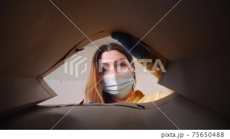 woman face in mask opens a packet bag of food meal. contactless delivery fast food quarantine coronavirus concept. adult girl face in mask gloves pulls food out of a paper bag delivery safety 75650488