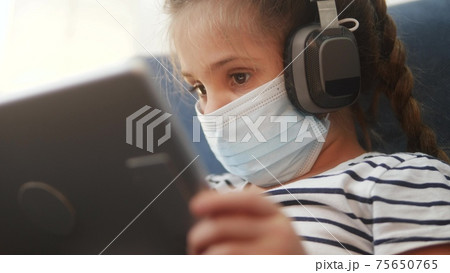 distance learning online lessons. child girl with digital tablet in mask studying remotely at home. education coronavirus online lessons lockdown concept. child learns distance learning school distance learning online lessons. child girl with digital tablet in mask studying remotely at home. education coronavirus online lessons lockdown concept. child learns distance learning school 75650765