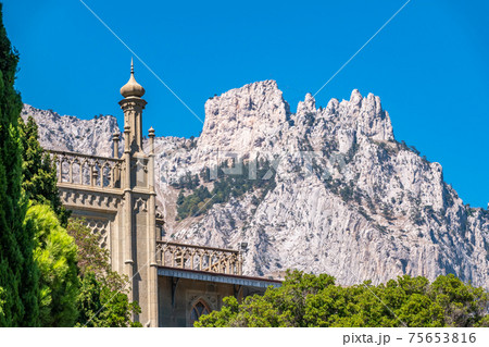The walls and towers of the old palace on the background of high mountains and blue sky 75653816