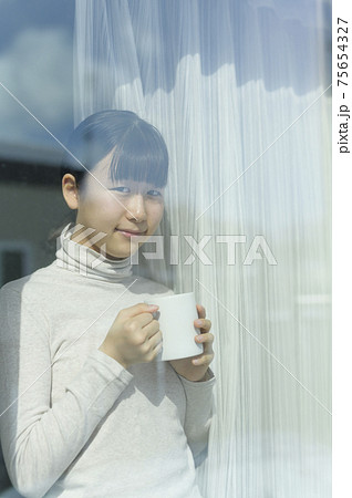窓辺でコーヒーを飲む女の子 75654327