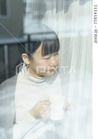 窓辺でコーヒーを飲む女の子 75654331
