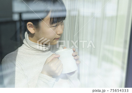 窓辺でコーヒーを飲む女の子 窓辺でコーヒーを飲む女の子 75654333