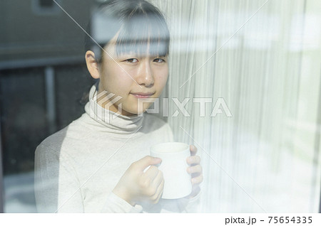 窓辺でコーヒーを飲む女の子 75654335