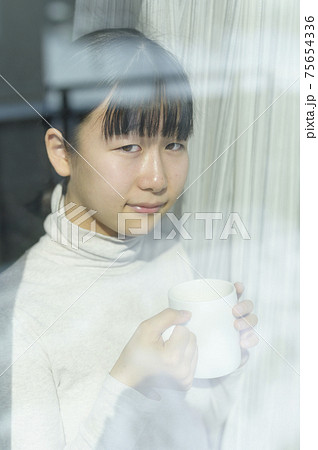 窓辺でコーヒーを飲む女の子 75654336