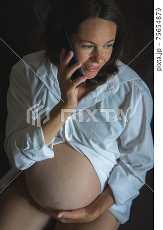 From above Pregnant woman speaking on smartphone 75654879