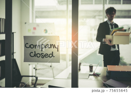 Company closed on windows of an empty office with business man packing beloning walking out of business by economic recession concept. 75655645