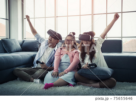 Asian Family with Down Syndrome kid is playing VR glasses Game on the floor with winning expression. 75655646