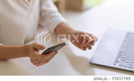 Female hands holding smartphone and credit card to online payment 75657760