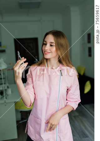 Manicure tools in hands of female manicurist wearing pink uniform in studio Manicure tools in hands of female manicurist wearing pink uniform in studio 75659617