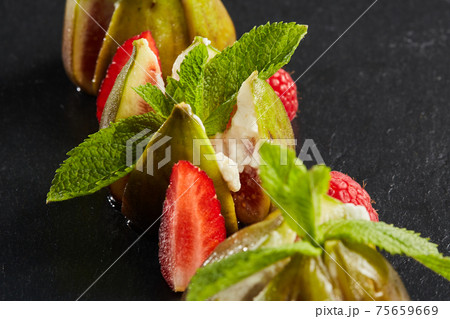 The figs with cheese garnished with mint leaves and raspberries and strawberries. Mediterranean cuisine. Shallow dof. The figs with cheese garnished with mint leaves and raspberries and strawberries. Mediterranean cuisine. Shallow dof. 75659669