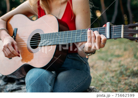 Creative hobbies, guitar lessons, playing musical instruments. Acoustic guitars for beginners. Young blonde woman with Acoustic guitar outdoor 75662599