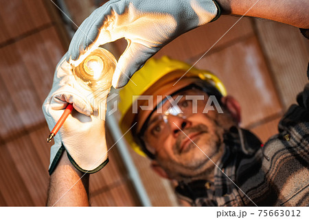 Electrician at work with safety equipment on a residential electrical system. Electricity. Electrician at work with safety equipment on a residential electrical system. Electricity. 75663012