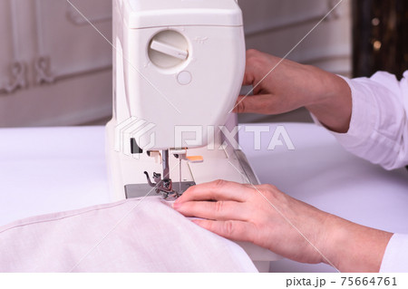 A seamstress working on a sewing machine.  75664761