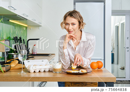 Woman dips toast in fried egg Woman dips toast in fried egg 75664838