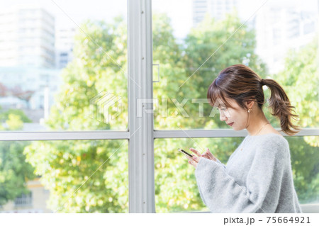 スマホ　窓際の女性　ビジネスシーン 75664921