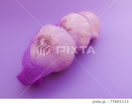 Garlic in net. Garlic packaging nets. Three garlic heads packaged in a mesh bag. Fresh garlic head wrapped in mesh bag Garlic in net. Garlic packaging nets. Three garlic heads packaged in a mesh bag. Fresh garlic head wrapped in mesh bag 75665113