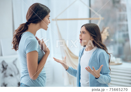 Screaming emotional girl standing in front of mom Screaming emotional girl standing in front of mom 75665270