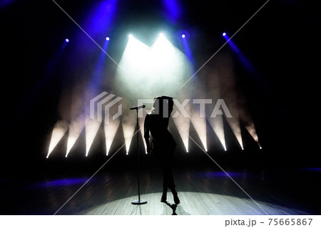 Silhouette of singer on stage. Dark background, smoke, spotlights. Silhouette of singer on stage. Dark background, smoke, spotlights. 75665867