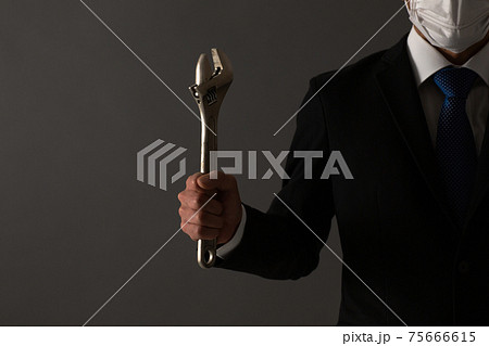 レンチを持つ男性　スーツ　手元 75666615
