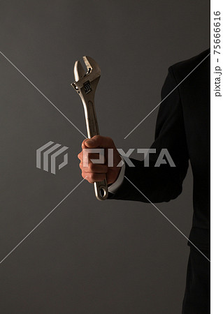 レンチを持つ男性　スーツ　手元 75666616