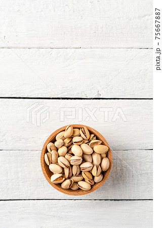 Delicious pistachios in bowl on white wooden background with copyspace. Top view 75667887
