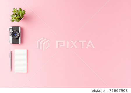 Modern workspace concept with photo camera, notebook and pen on pink background with copyspace. Office desktop. Top view Modern workspace concept with photo camera, notebook and pen on pink background with copyspace. Office desktop. Top view 75667908