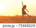 Elegant woman with long hair in long dress dancing elegant on sand in desert. Sunrise, backlight photo 75668029
