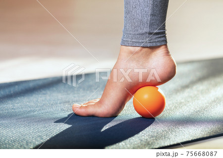 Myofascial release of hyper-movable muscles of the foot with a massage ball on a gymnastic mat at home. Prevention of leg fatigue after wearing high heel shoes 75668087