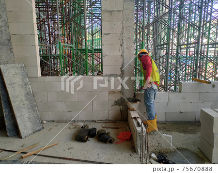 SEREMBAN, MALAYSIA -MARCH 15, 2020: Blockwork by construction workers at the construction site. Workers laying the AAC brick and stacked it together using mortar to form the wall.  75670888